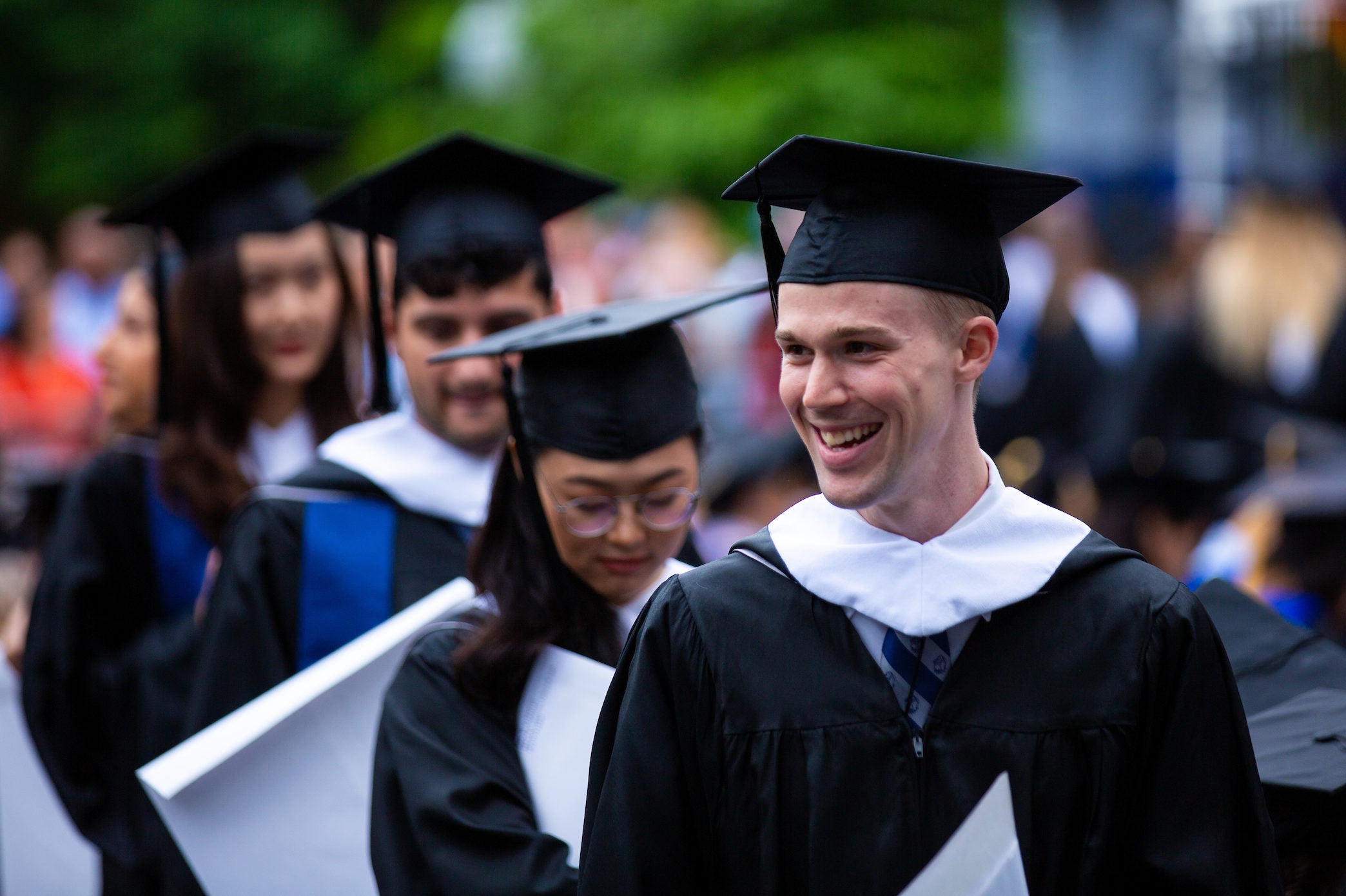 Recent graduates carrying their diplomas at Commencement