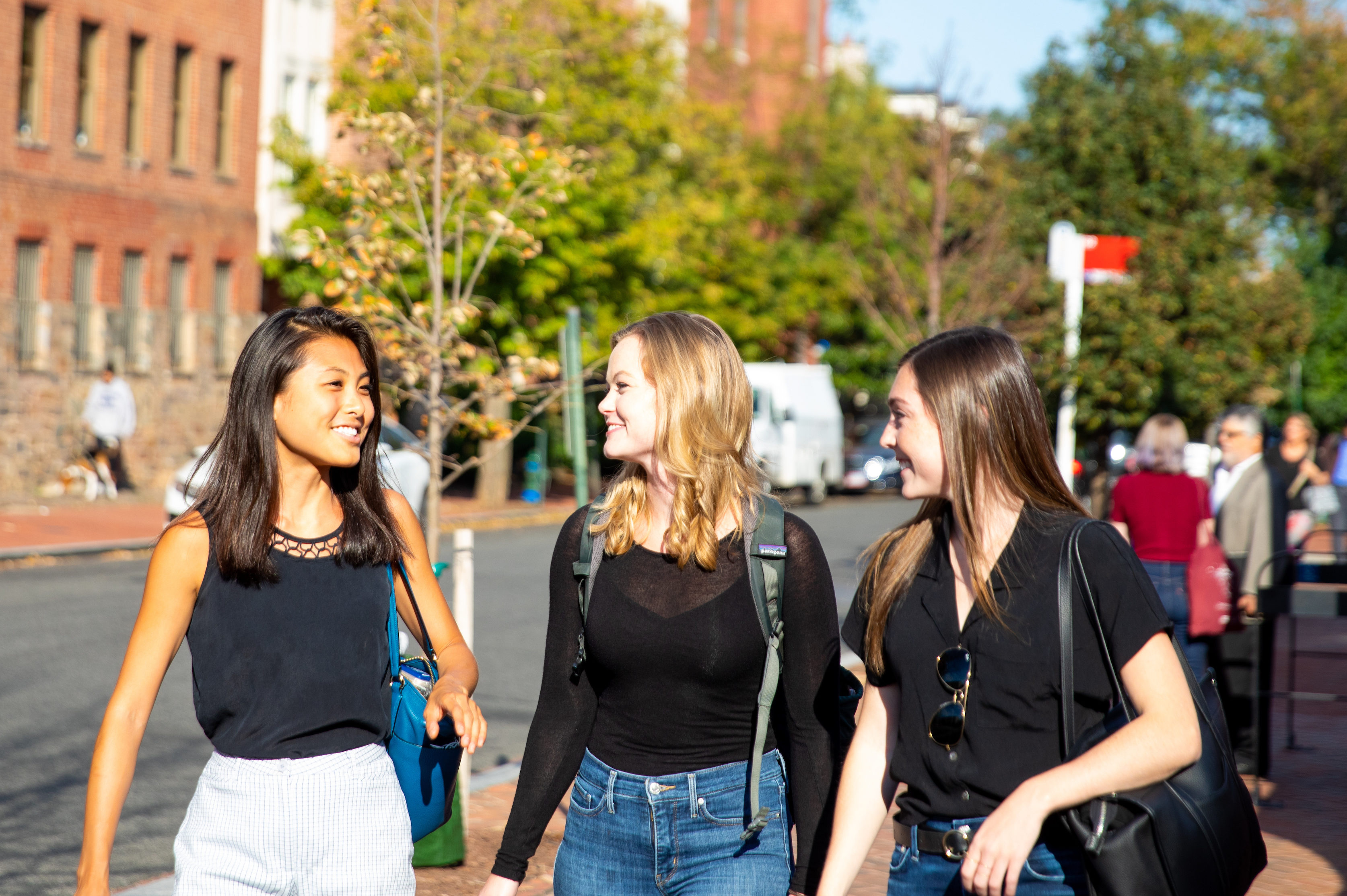 Three students talk while walking across campus