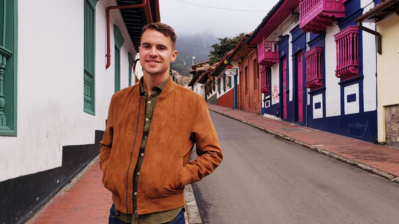 Sam Riddell in front of a row of houses in Colombia