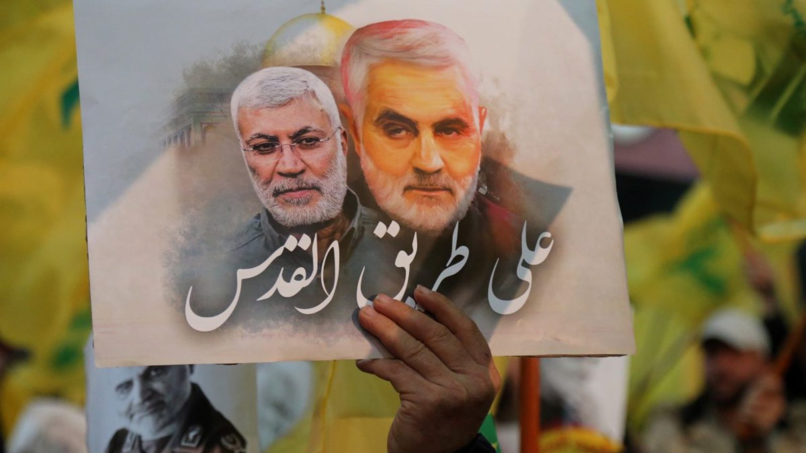 A photo of a hand holding up a drawing of Qassem Soleimani