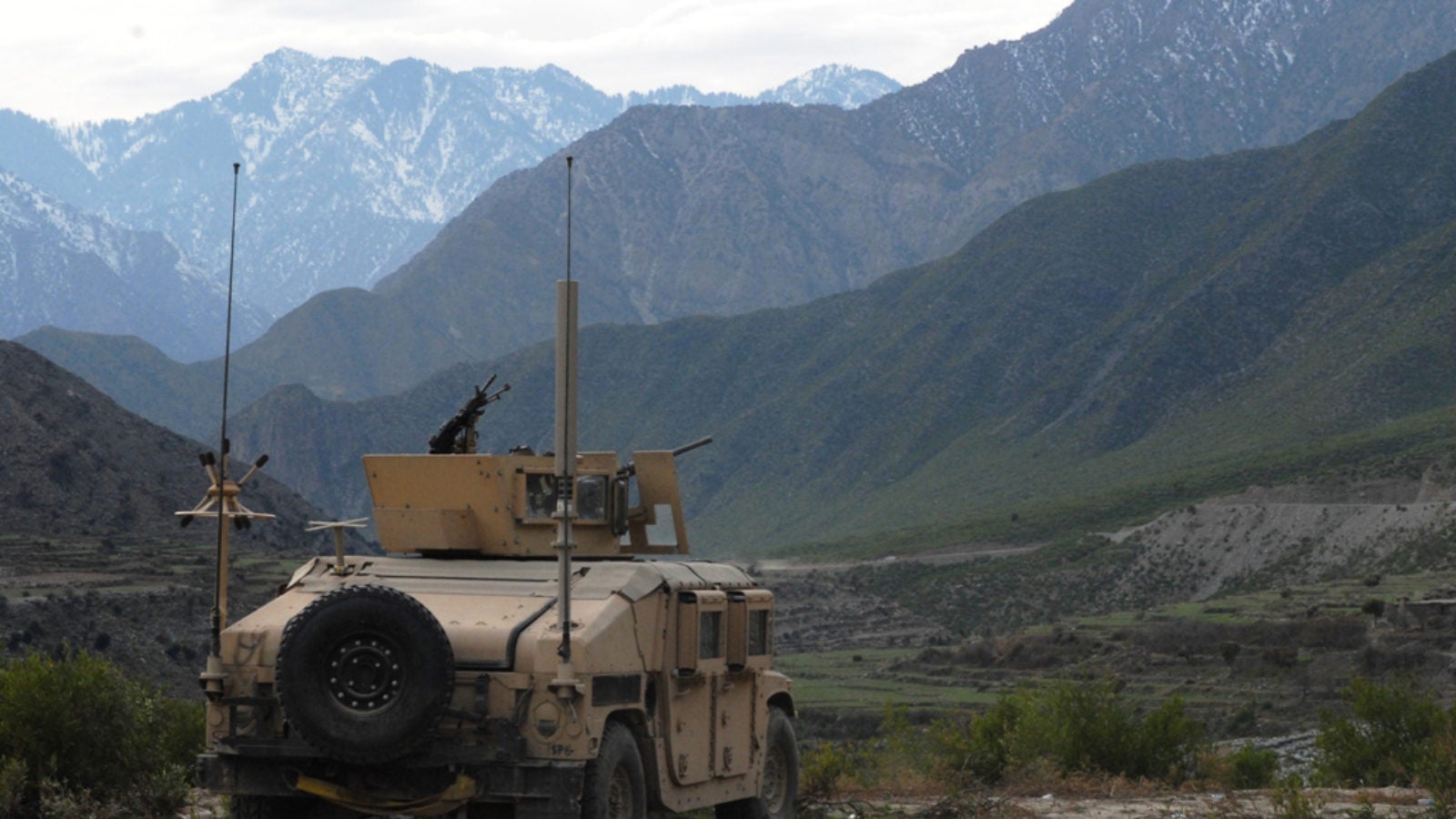 U.S. Army Humvee on patrol in front of mountains in Afghanistan