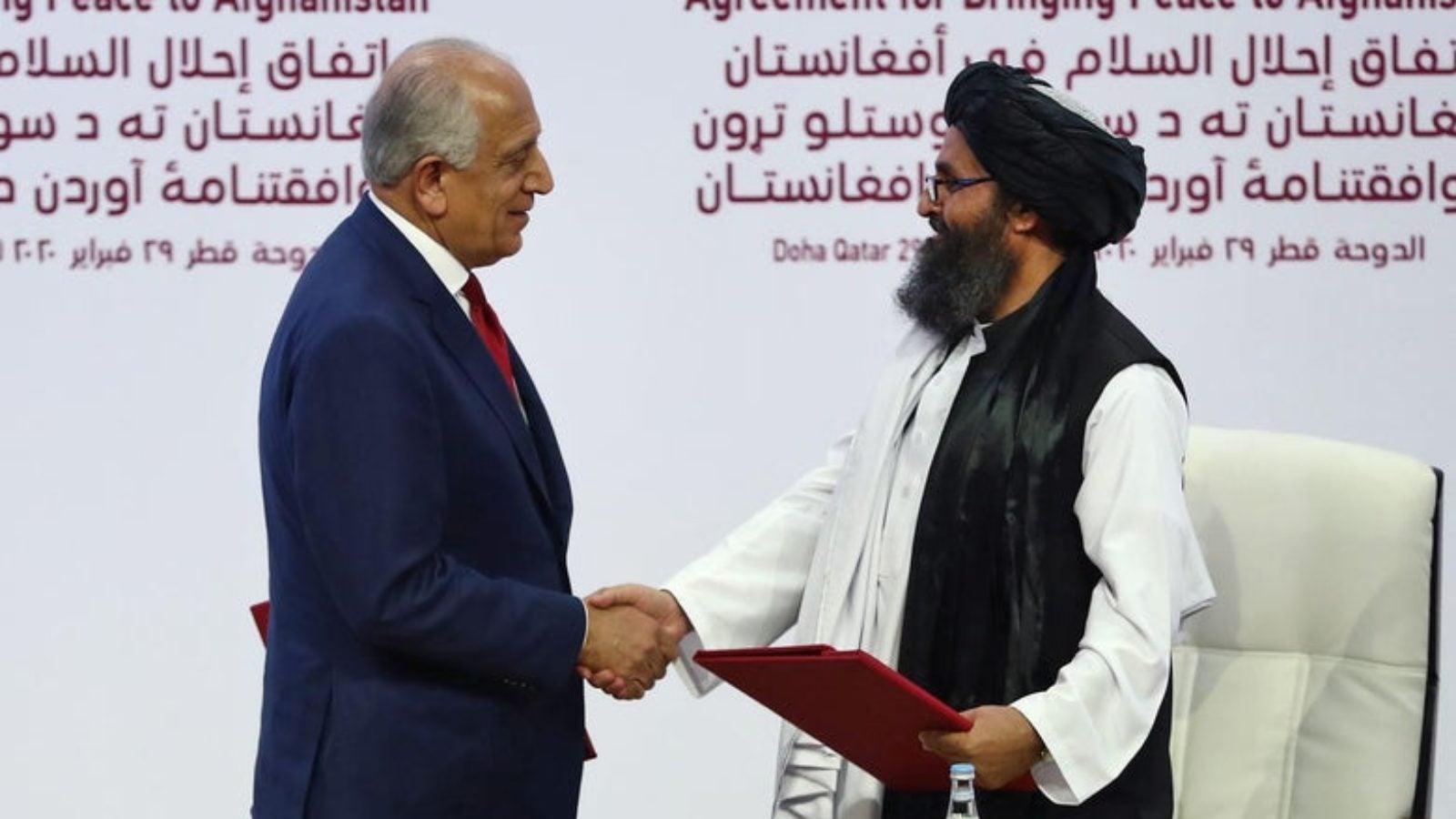 U.S. peace envoy Zalmay Khalilzad, left, and Mullah Abdul Ghani Baradar, the Taliban&#039;s top political leader, shake hands after signing a peace agreement between Taliban and U.S. officials in Doha, Qatar.