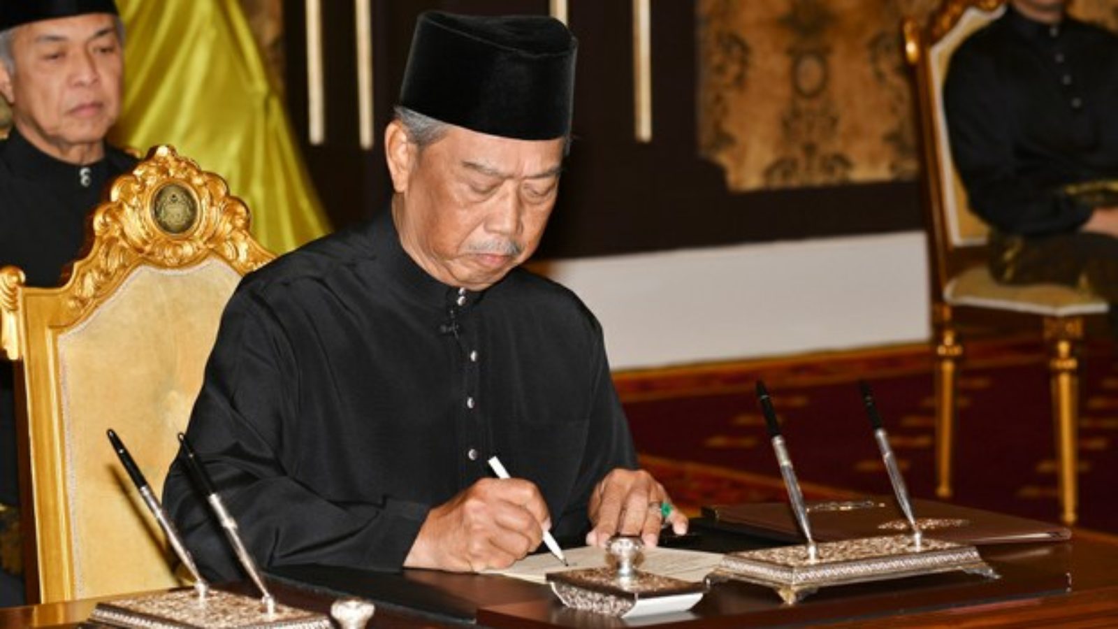 Malaysian Prime Minister Muhyiddin Yassin signs appointment documents after taking the oath of office in front of the king at the National Palace in Kuala Lumpur