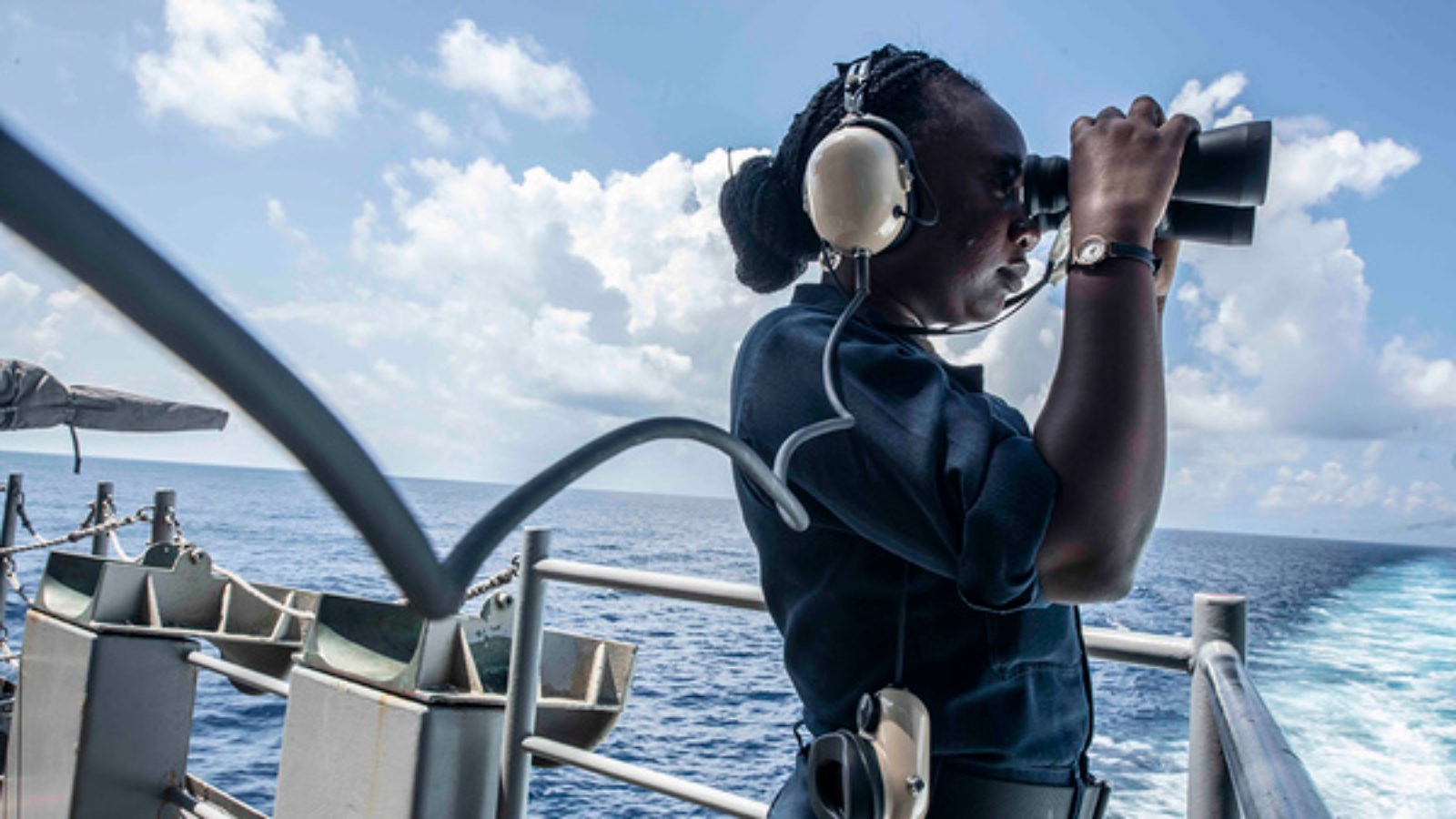 A seaman uses binoculars while standing aboard the U.S. Navy aircraft carrier USS Ronald Reagan.