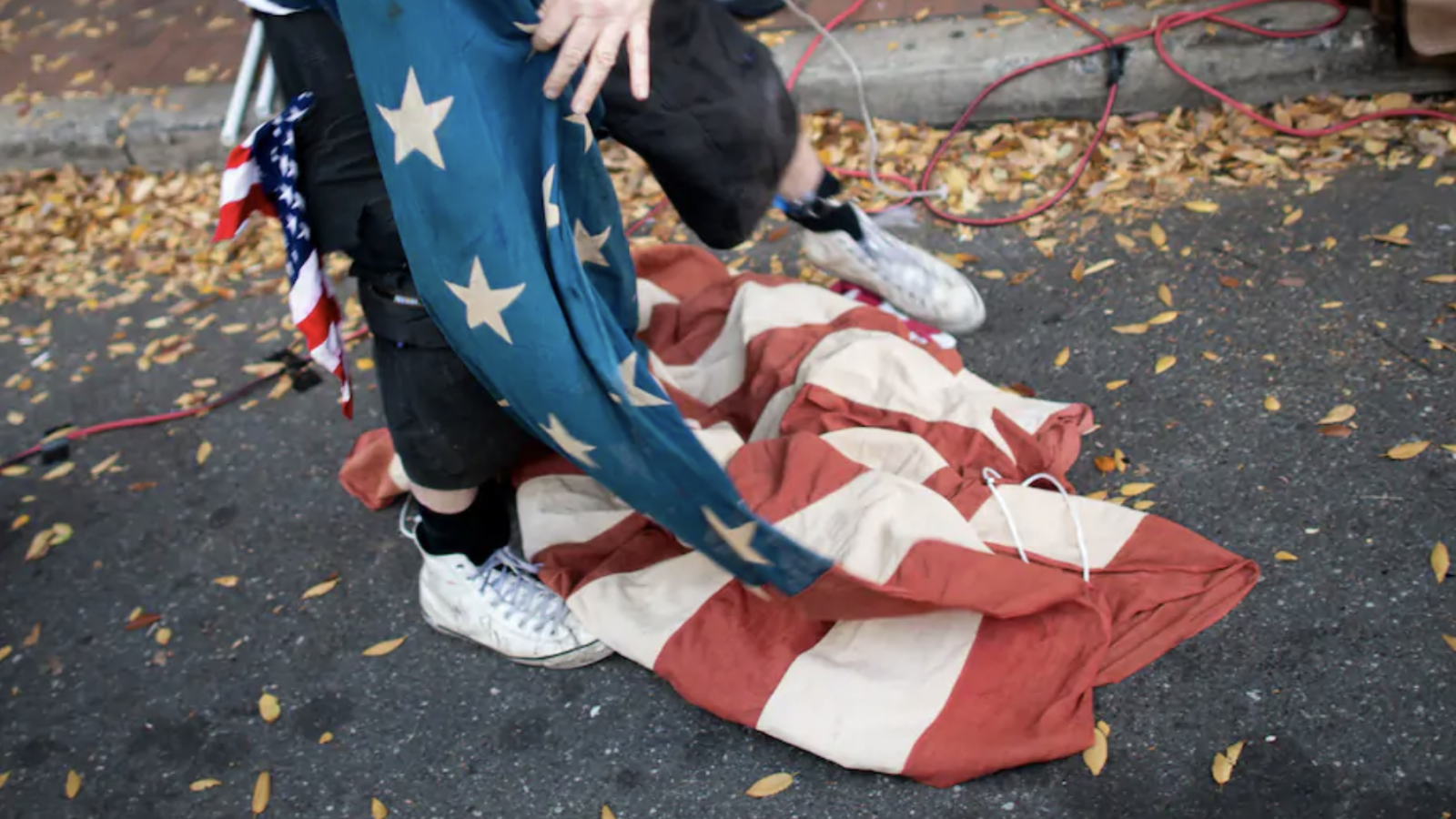 A hand unfurls an American flag from the ground.