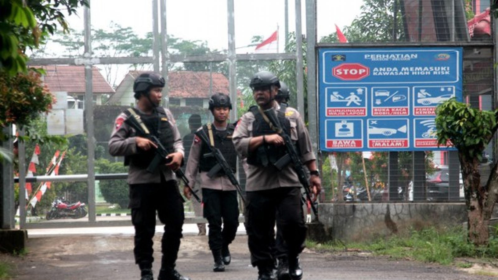 Four security personnel patrol the perimeter of a prison in Indonesia