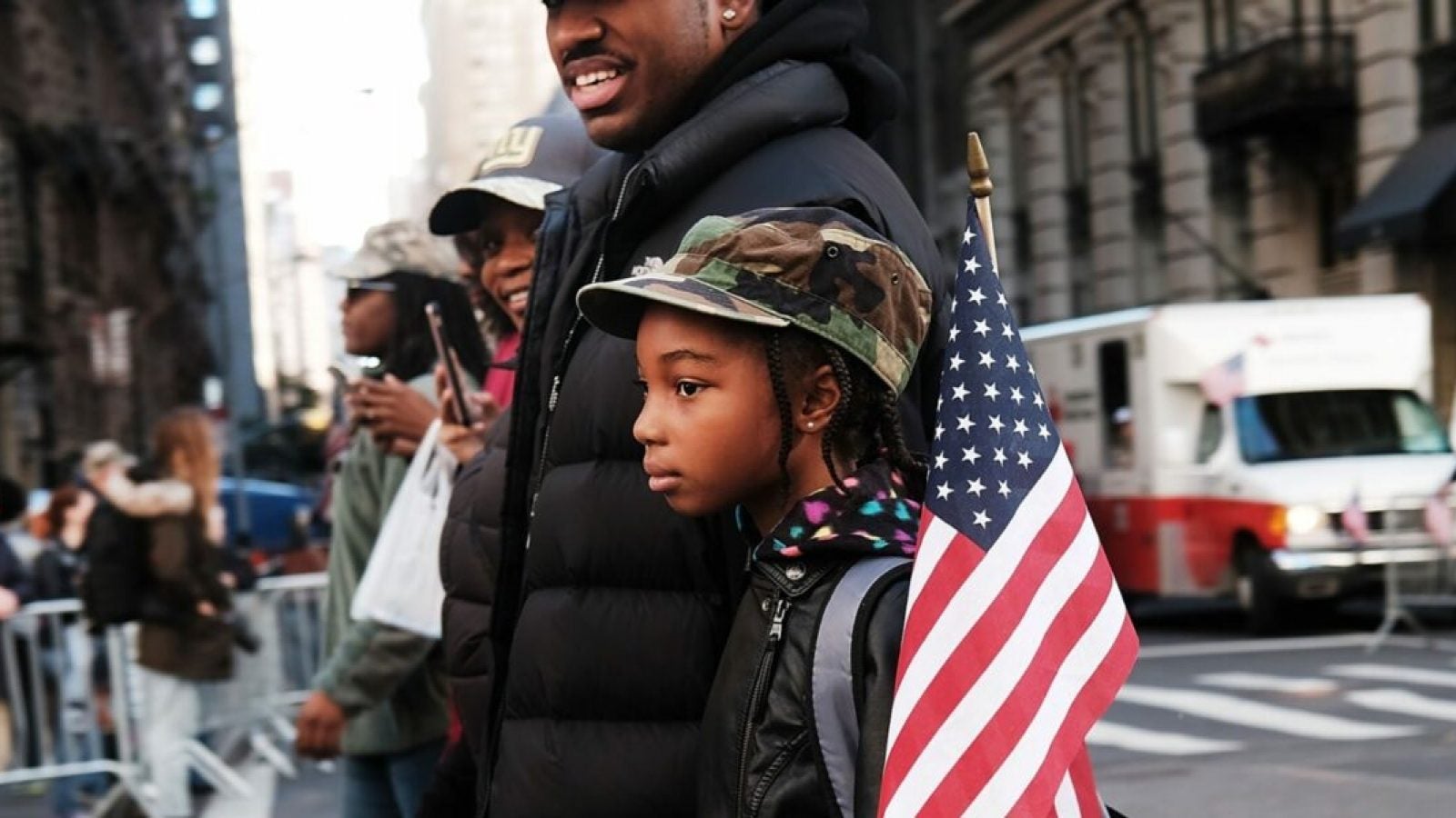 A family stands in the street with an American flag