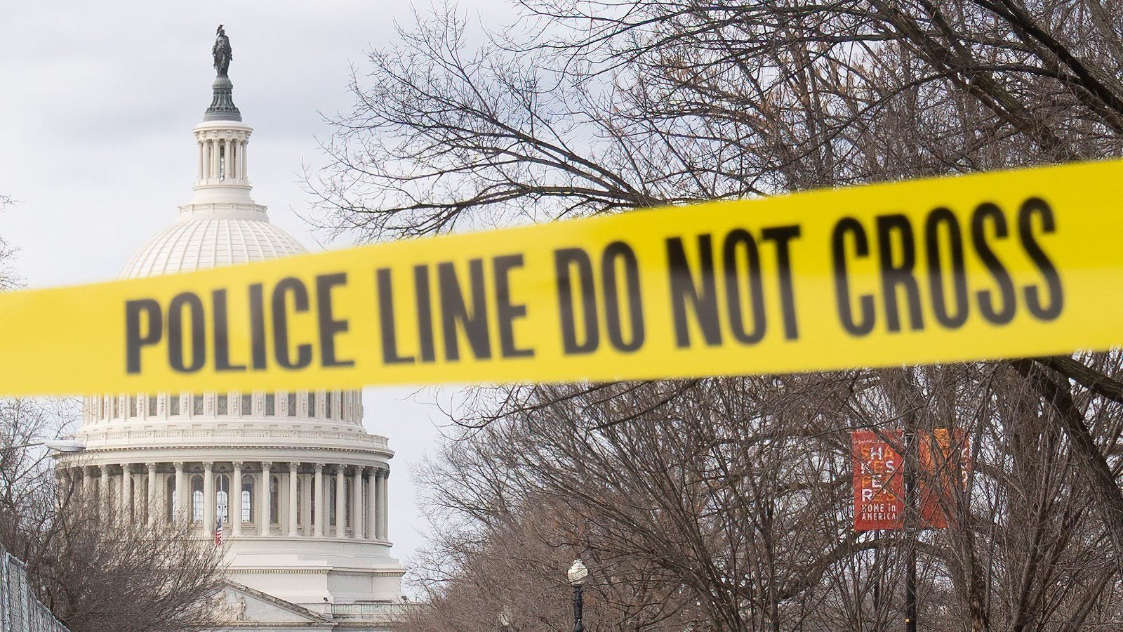 The Capitol Building is framed by a yellow police tape that reads &quot;Police Line Do Not Cross&quot; in the foreground.