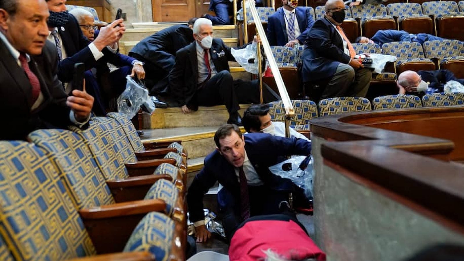 People duck beneath seats in the House gallery