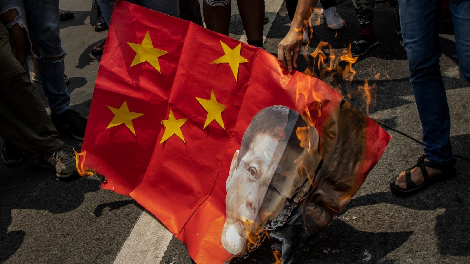 A mock Chinese flag with Rodrigo Duterte&#039;s face is burned by protestors on the street