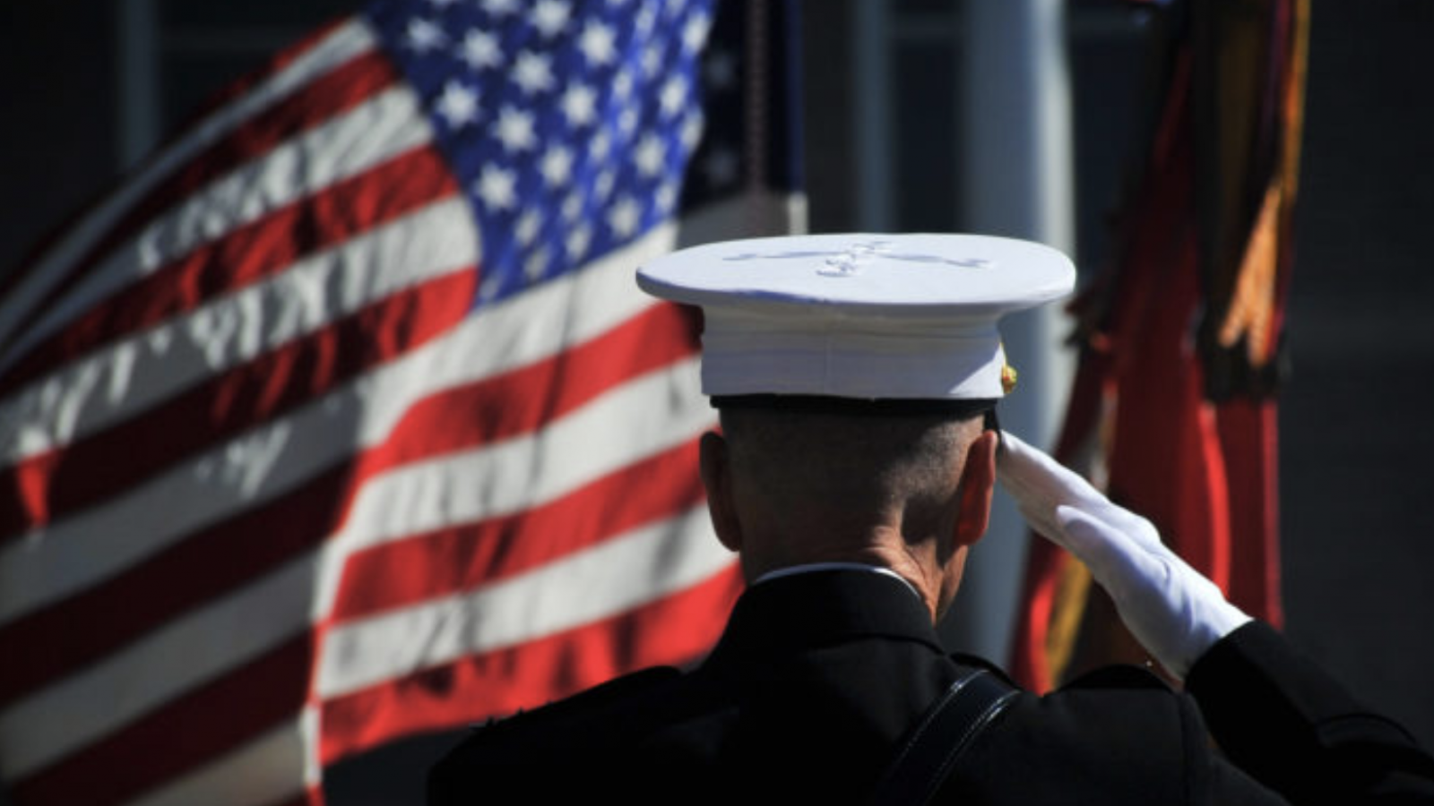 A man in a military uniform salutes U.S. flags