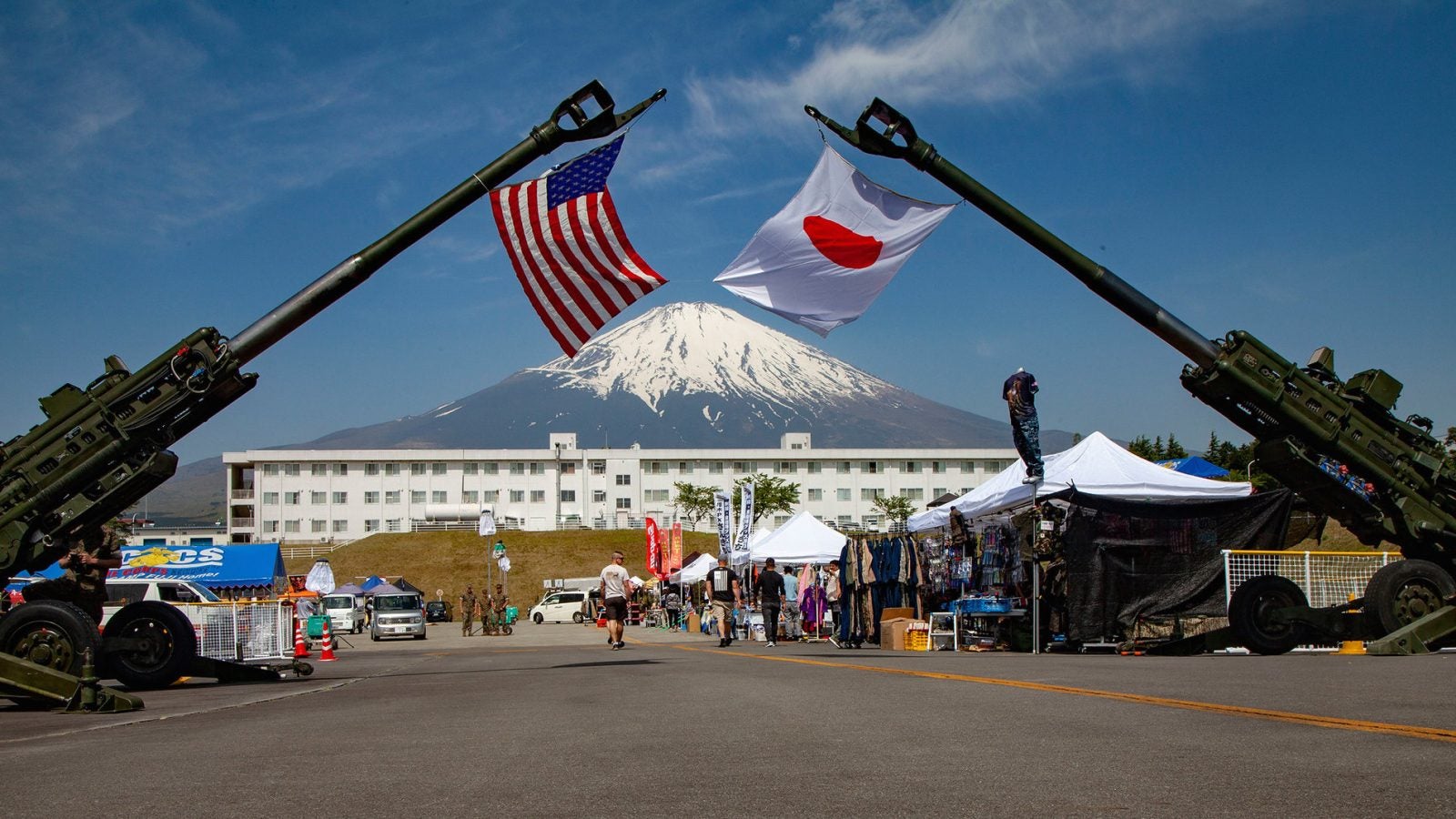 Two artillery weapons hoist the Japanese and U.S. flags with Mount Fuji in the background