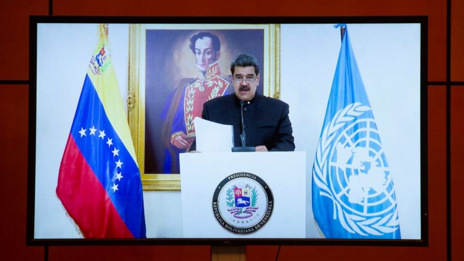 Nicolas Maduro is flanked by a Venezuelan and UN flag as he stands at a podium for a speech