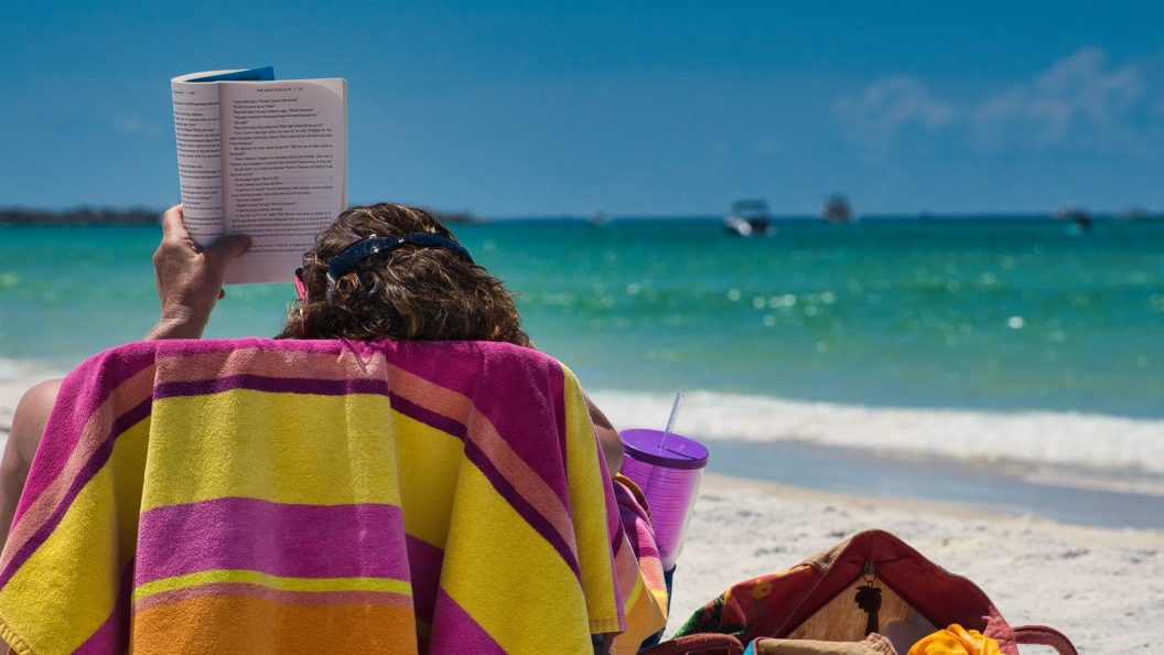 A person reads in a beach chair on the beach