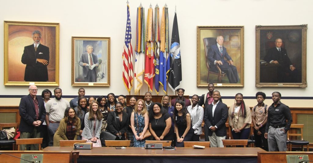 Students and staff pose in the House Armed Services Committee chamber