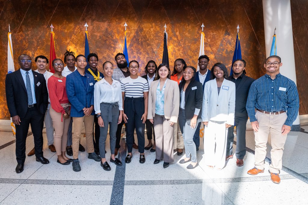 The Summer Institute students stand together in front of eight flags at the National Security Agency. 